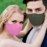 Couple wearing pink and olive green cloth masks outdoors