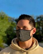Man in a tan hoodie wearing a heather gray cotton mask outside