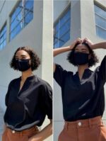 Woman in a black blouse wearing a black cotton mask outdoors